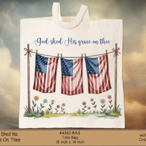 White canvas tote bag featuring the blue script phrase “God shed His grace on Thee” and a row of American flag bunting with flowers below.